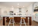 Kitchen with white cabinets, stainless steel appliances, island with seating, and hardwood floors at 204 Phillips Ln, Alpharetta, GA 30009