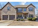 Charming two-story home featuring a brick facade, covered porch, and well-manicured landscaping at 527 Mossycup Dr, Fairburn, GA 30213