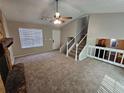 Bright living room with plush carpeting, a cozy fireplace, and a staircase leading to the upper level at 6301 Creekford Dr, Lithonia, GA 30058