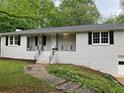 Quaint house with white brick and dark shutters and front porch with decorative railing at 1871 Kinridge Rd, Marietta, GA 30062