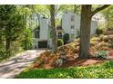 Beautiful home exterior featuring mature trees, flowering shrubs, a quaint water fountain, and a long driveway at 3727 Cline Se Dr, Smyrna, GA 30082