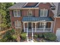 Close-up of a classic brick home featuring a welcoming front porch with white columns and manicured landscaping at 1812 Mountain Lake Nw Dr, Kennesaw, GA 30152