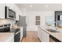 Well-equipped kitchen showcasing stainless steel appliances, granite counters, and white cabinetry at 1002 Sutherland Lane (Lot 36), Lawrenceville, GA 30043