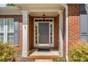 Covered front entry featuring a decorative door with sidelights and a brick surround at 1330 Badingham Dr, Cumming, GA 30041