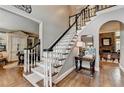 Elegant foyer with hardwood floors, white staircase with black trim, and views into the living room at 10355 Oxford Mill Cir, Johns Creek, GA 30022