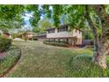 Side yard shot of a two-story home with a brick foundation and light-colored siding surrounded by mature trees at 2921 Country Squire Ln, Decatur, GA 30033