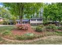 Exterior front yard view of the home showing a lush, manicured landscape with a mature tree and flower bed at 2921 Country Squire Ln, Decatur, GA 30033