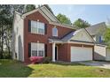 Classic brick home featuring a two-car garage and a cozy, inviting front yard with mature plants at 415 Clairidge Sw Ln, Lawrenceville, GA 30046