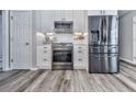 Kitchen with stainless steel appliances, white cabinetry, and wood-look flooring at 305 Nobleman Way, Canton, GA 30114