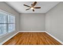 Cozy bedroom featuring hardwood floors, a ceiling fan, and natural light from a large window at 3634 Lost Oak Dr, Buford, GA 30519