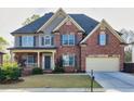 A two-story brick home showcasing a well-maintained lawn and a classic architectural design at 3634 Lost Oak Drive, Buford, GA 30519