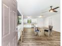 Open-concept living space with modern wood floors, ceiling fan, and kitchen with white cabinets in the background at 8405 Military Way, Douglasville, GA 30134