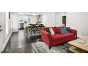Open-concept living room with dark floors, a large red sofa, leading to a kitchen and dining area at 1084 Regent Sw St, Atlanta, GA 30310