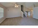 Spacious living room featuring neutral carpet, vaulted ceilings, a ceiling fan, and staircase at 5820 Wellborn Oaks Ct, Lithonia, GA 30058