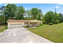 Wide angle of a charming one-story home with front porch, attached garage and lush green lawn at 645 Camp Perrin Rd, Lawrenceville, GA 30043