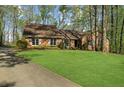 Beautiful brick home with green lawn, mature trees, and a paved driveway leading to the property at 11815 Mountain Laurel Dr, Roswell, GA 30075