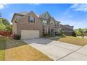 Brick and stone home with a well-maintained lawn, complemented by an ample driveway and lush greenery at 4279 Two Bridge Dr, Buford, GA 30518