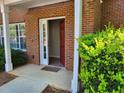Close-up of the condo's front door, with a trimmed green bush in front of the red-brick facade at 101 Spring Heights Se Ln # 1, Smyrna, GA 30080
