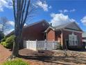 Brick home featuring a white picket fence, trimmed hedges, mature trees, and a well-manicured lawn and garden at 119 Holiday Rd # 704, Buford, GA 30518