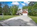 Traditional two-story home with a large driveway and a manicured lawn surrounded by mature trees at 2979 Sweetbriar Walk, Snellville, GA 30039
