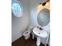 Stylish powder room featuring a pedestal sink and modern fixtures with an oval window at 4487 Kerrington Ave, Sugar Hill, GA 30518