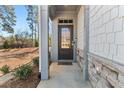 Covered front entry with decorative stone accents, enhanced by the natural light and landscaped surroundings at 1041 Cherryfield Run, Marietta, GA 30008