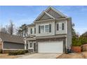 Charming two-story home with a gray exterior, stone accents, black shutters, and a two-car garage at 9032 Jim Purcell Dr, Covington, GA 30014