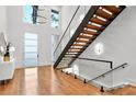 Bright foyer features wood floors, stairs with glass railings, and a modern light fixture at 820 Moores Mill Nw Rd, Atlanta, GA 30327