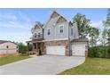 Lovely two-story home with a brick and gray exterior, covered porch, and a three-car garage at 7515 Woolf Way, Cumming, GA 30028