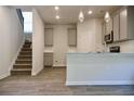 Open-concept kitchen and stairs featuring modern appliances, gray cabinets, and wood-look flooring at 679 Egrets Landing Lot 57, Covington, GA 30014