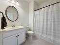 Bright bathroom with a white vanity, round mirror, and a shower with a striped curtain at 5515 Allegre Pl, Cumming, GA 30028