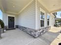 Inviting front porch with stone accents, a dark front door with a wreath, and gray siding at 5515 Allegre Pl, Cumming, GA 30028