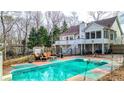 A turquoise swimming pool is surrounded by seating, a two-story deck, and mature trees at 1074 Fieldstone Dr, Canton, GA 30114