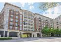 Street-level view of the Aramore building featuring a brick facade, covered entryway, street-level retail and mature trees at 2277 Peachtree Ne Rd # 310, Atlanta, GA 30309