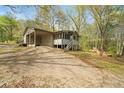 A tan home with a carport and screened-in porch is surrounded by beautiful mature trees at 5026 Daniel Mill Rd, Winston, GA 30187