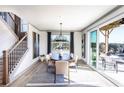 Bright dining area featuring a modern chandelier, large windows, sliding glass doors, and staircase access at 7630 Homer Dr, Cumming, GA 30028
