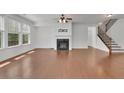 Spacious living room with hardwood floors, fireplace, staircase access, and natural light from large windows at 21 Belmore Manor Dr, Suwanee, GA 30024