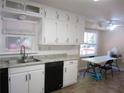 Well-lit kitchen with white cabinets, stainless steel sink, black dishwasher and adjacent dining area at 2107 Briarwood Ct, Snellville, GA 30078