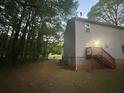 Rear view of a two-story house with a deck and stairs, surrounded by lush trees at 691 Aberdeen Dr, Stone Mountain, GA 30083