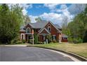 Elegant brick home featuring manicured lawn, mature trees, and circular driveway at 4799 Winterview Ln, Douglasville, GA 30135