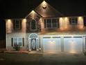 Night view of a two-story home with stone accents, attached two-car garage and illuminated driveway at 7228 Silverleaf Cir, Fairburn, GA 30213