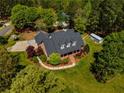 Aerial view of a beautiful brick home on lush landscaped grounds with mature trees and an outbuilding at 200 Sugar Mill Ln, Canton, GA 30115