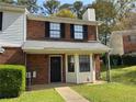 Traditional brick-front townhome featuring black shutters, covered porch, and green lawn at 1477 Springleaf Se Cir, Smyrna, GA 30080