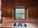 Kitchen with wood cabinets, countertops, stainless steel double sink and a window with a view of the backyard at 3798 Lee Ridge Sw Way, Lilburn, GA 30047