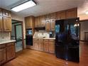 A kitchen featuring wood cabinets, black appliances, hardwood floors and great counter space at 3798 Lee Ridge Sw Way, Lilburn, GA 30047