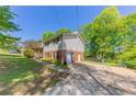 View of the home, garage and driveway, featuring a large lawn, mature trees, and partial fencing at 4170 N Quail N Dr, Douglasville, GA 30135