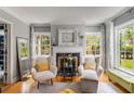 Bright living room features hardwood floors, a decorative fireplace, and two chairs with ottomans by large windows at 1157 Hancock Ne Dr, Atlanta, GA 30306