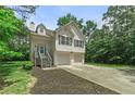Charming two-story home features a two-car garage, light siding, green trees and neatly landscaped front yard at 1303 Flat Shoals Rd, Atlanta, GA 30349