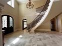 Elegant foyer boasts travertine tile, wrought iron staircase, and decorative trim, creating a grand entrance at 9390 Colonnade Trl, Johns Creek, GA 30022
