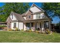 Beautiful two-story home featuring a well-manicured lawn, stone accents, and a welcoming front porch with outdoor furniture at 235 South St, Buford, GA 30518